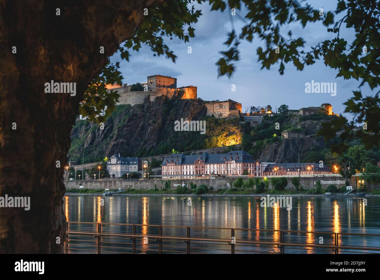 Deutschland, Nordrhein-Westfalen, Koblenz, Festung Ehrenbreitstein mit Blick auf Gebäude am Flussufer in der Abenddämmerung Stockfoto