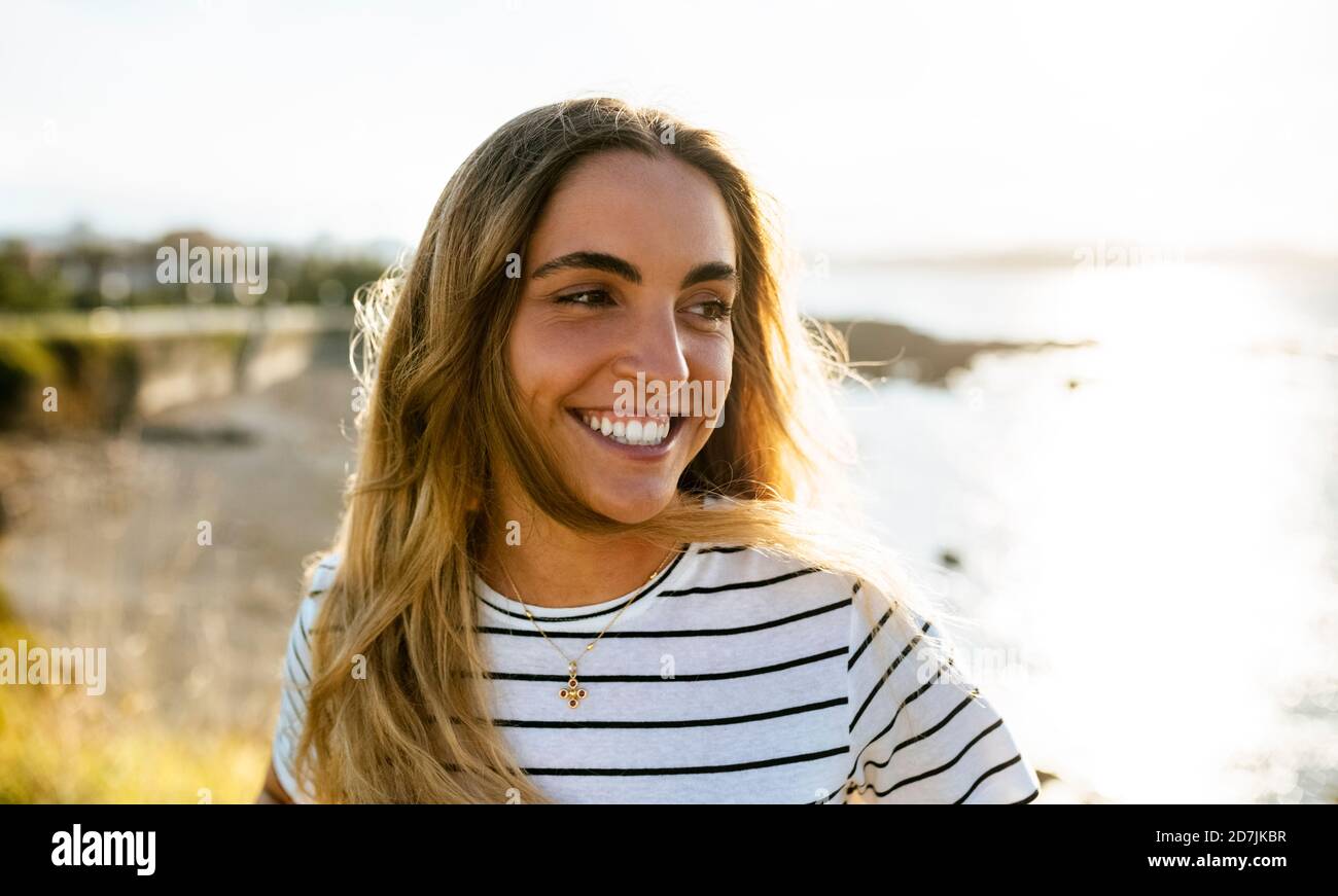 Glückliche junge Frau, die wegschaut, während sie das Wochenende am Strand verbringt An sonnigen Tagen Stockfoto
