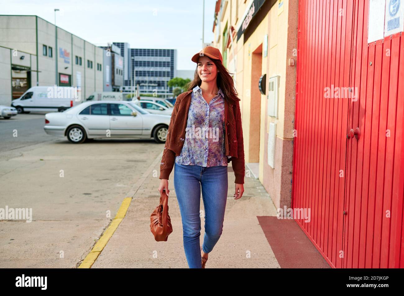 Junge Frau mit Geldbeutel zu Fuß auf der Straße in der Stadt Stockfoto