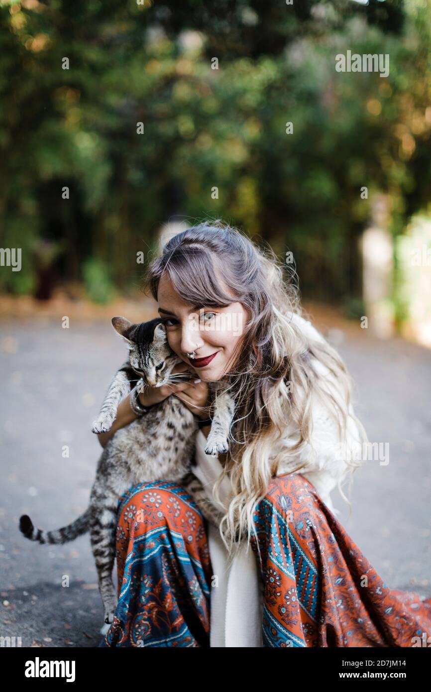 Frau umarmt Katze, während sie auf der Straße sitzt Stockfoto