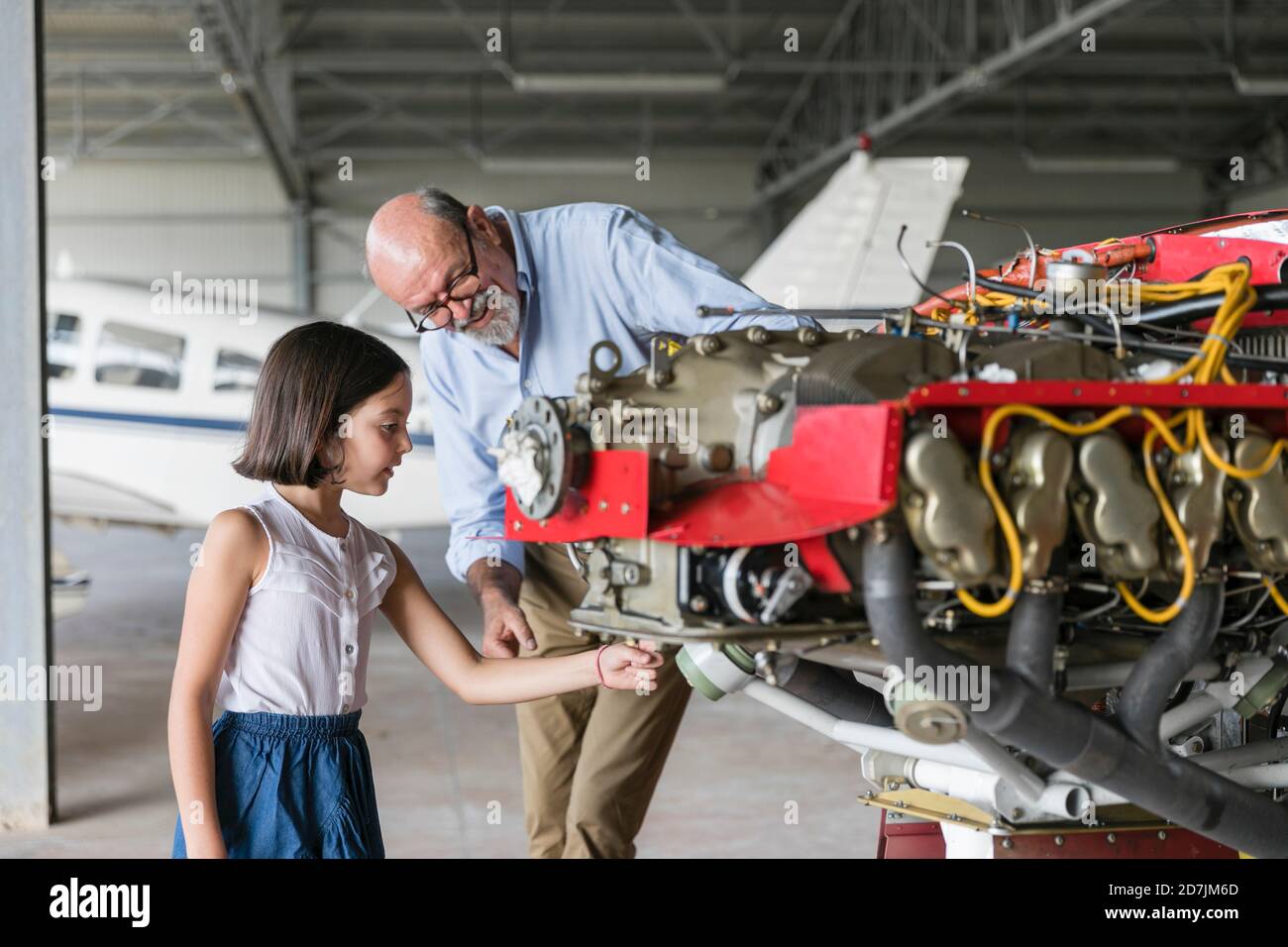 Großvater zeigt, wie man Flugzeug-Werkzeug zu Enkelin zu reparieren, während Im Hangar stehen Stockfoto