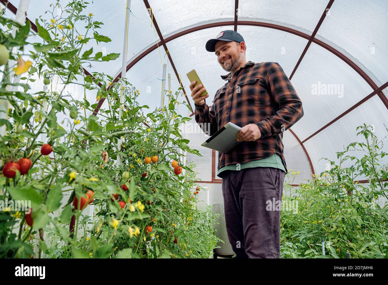 Lächelnder Mann mit Handy, während grüne Haus stehen Stockfoto