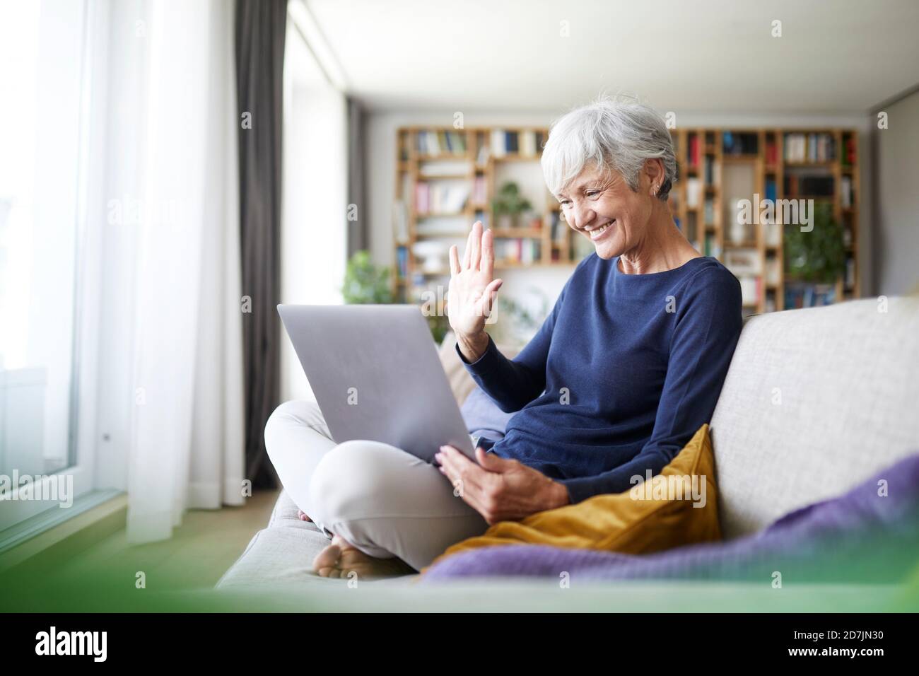 Ältere Frau macht hohe fünf bei Videoanruf während der Verwendung Laptop zu Hause Stockfoto