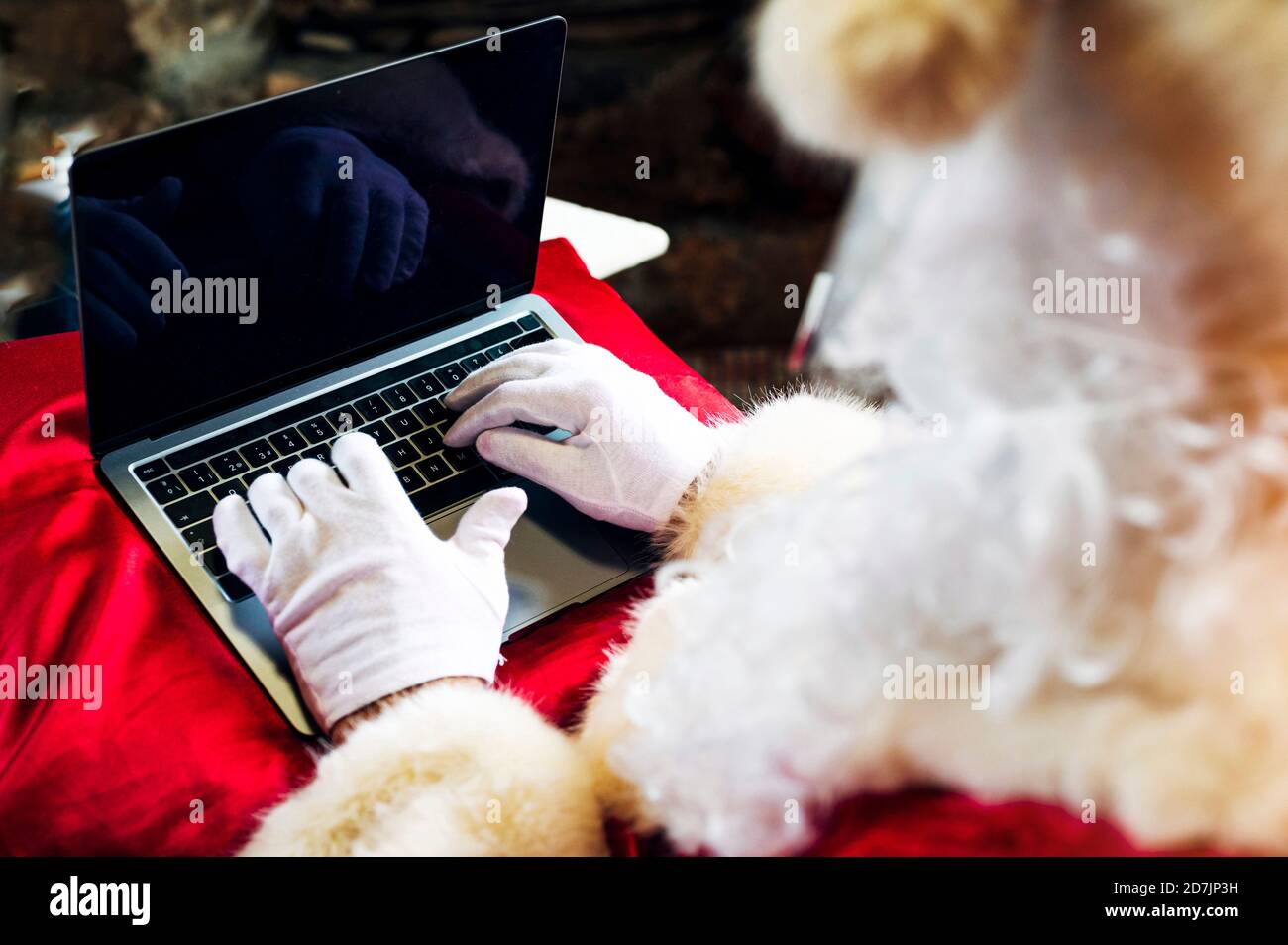 Mann trägt Weihnachtsmann Kostüm mit Laptop, während sitzen Zu Hause Stockfoto