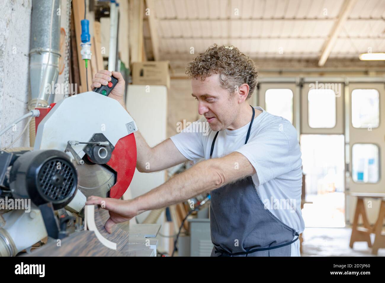Mann, der die elektrische Sägemaschine im Stand in der Werkstatt betreibt Stockfoto