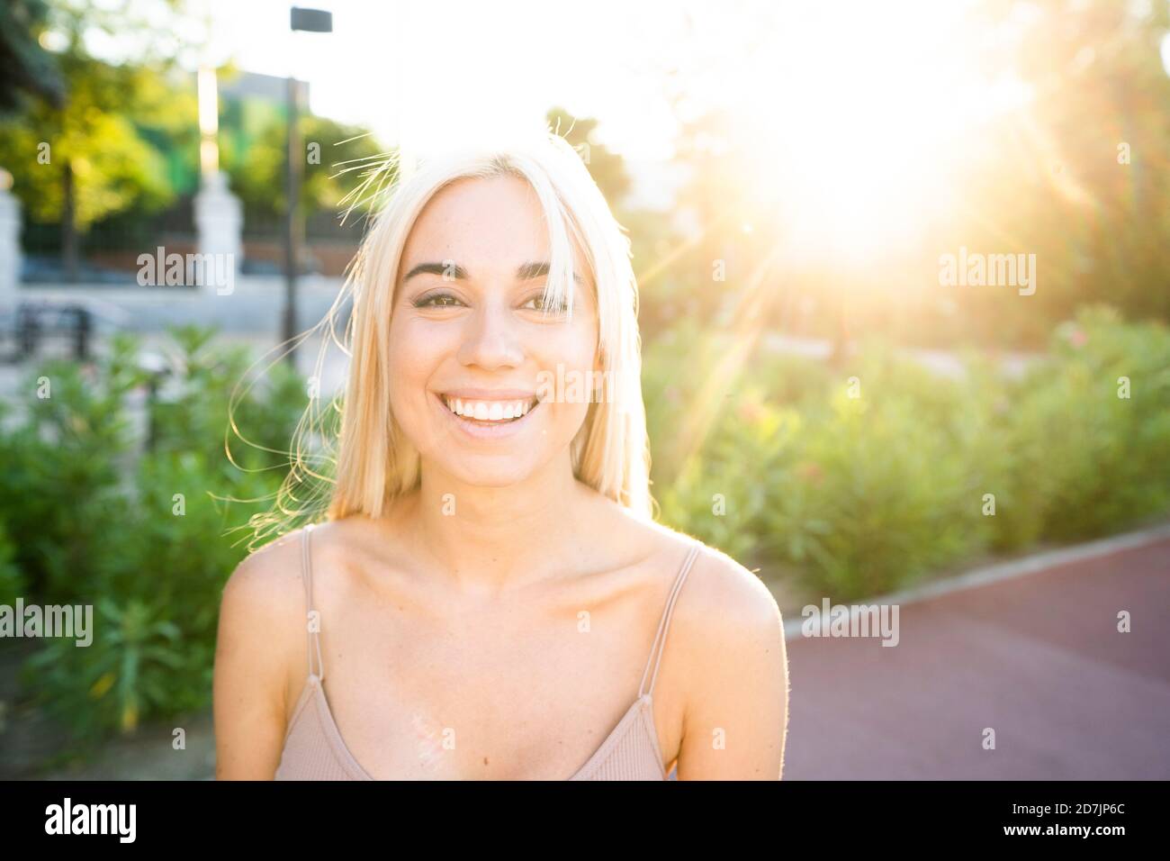Nahaufnahme einer lächelnden jungen Frau mit blonden Haaren im Park Bei Sonnenuntergang Stockfoto