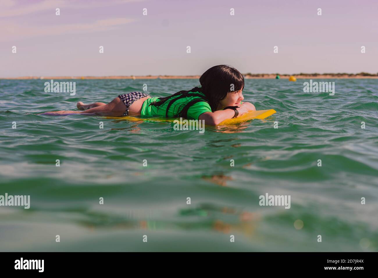 Mädchen liegt auf dem Body Board schwimmend auf dem Meer gegen den Himmel Bei Sonnenuntergang Stockfoto