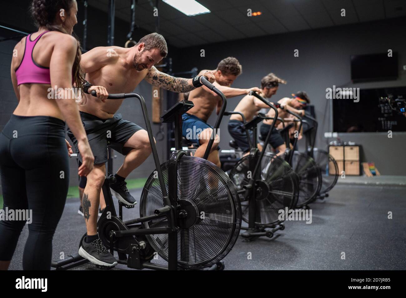Sportler sitzen auf dem Fahrrad während des Trainings im Fitnessstudio Stockfoto