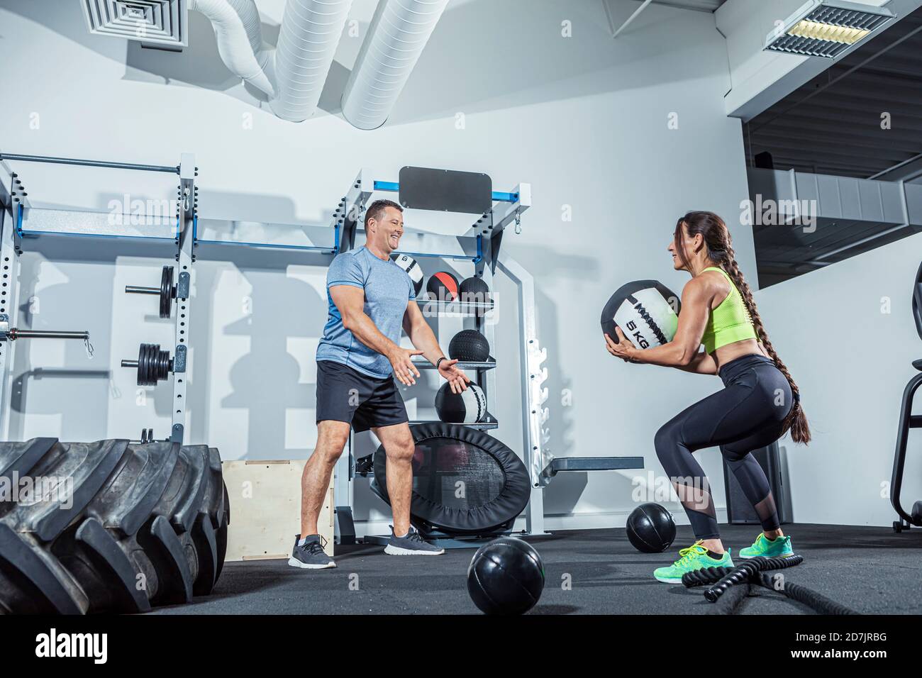 Männliche und weibliche Athleten trainieren mit Medizinball im Fitnessstudio Stockfoto