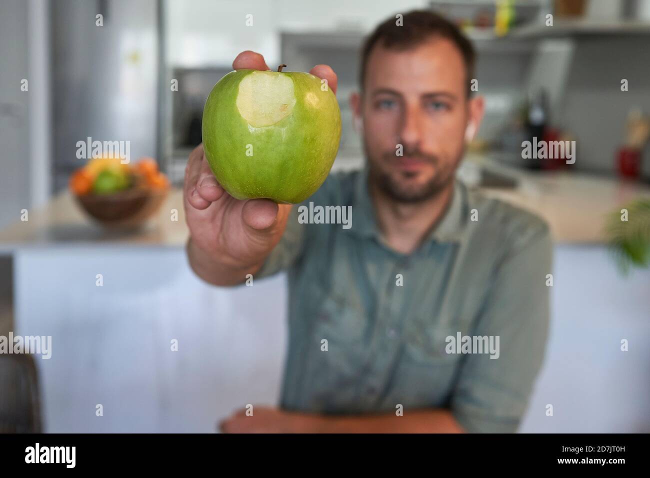 Mann zeigt Apfel gebissen, während er zu Hause sitzt Stockfoto