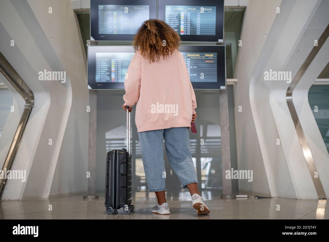 Junge Frau, die an Bord nach dem Flugplan checkt flughafen Stockfoto