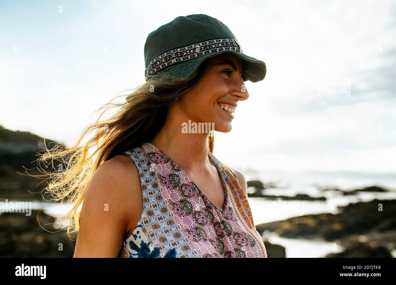 Fröhliche junge Frau im Hut weg schauen, während das Wochenende zu verbringen Am Strand Stockfoto