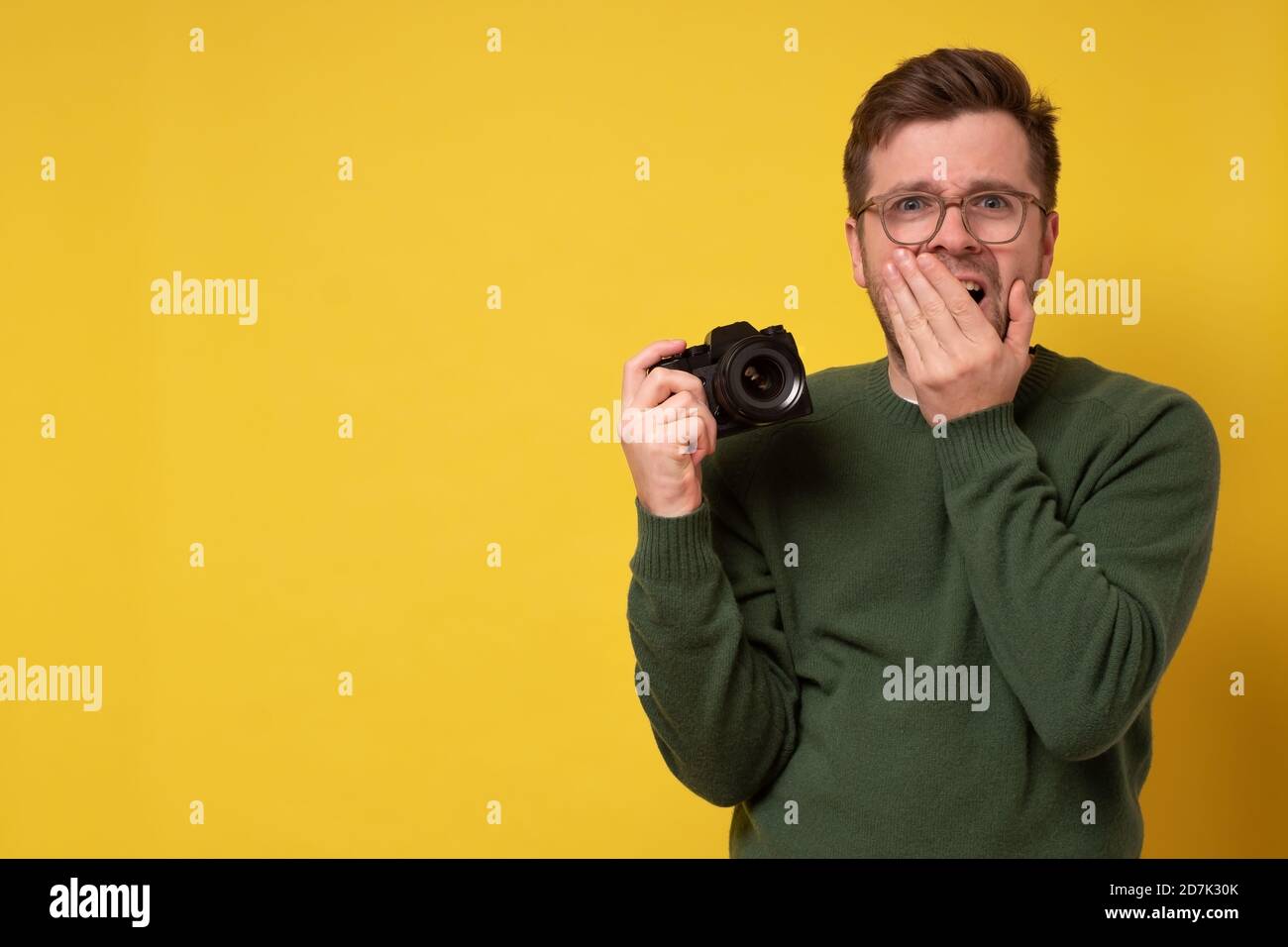 Junger Mann hält Fotokamera fotografieren mit Ergebnissen schockiert Stockfoto