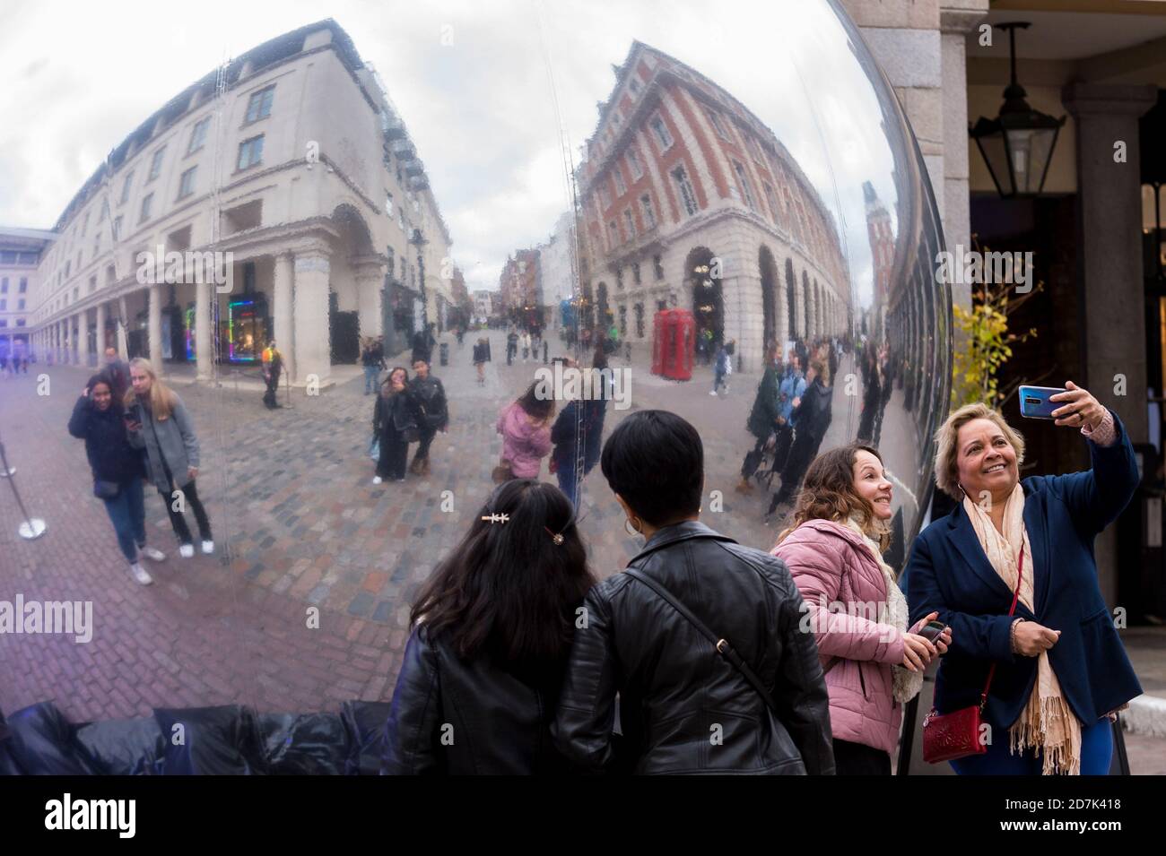 London, Großbritannien. 23. Oktober 2020. Passanten von interagieren mit einer neuen reflektierenden Skulptur namens 'AV', 2020, von Ben Cullen Williams in Covent Garden. Shaftesbury plc, Eigentümer von 16 Hektar Land in der Hauptstadt einschließlich Chinatown, Teile von Soho und Covent Garden, hat Notfallpläne angekündigt, um fast £300m zu erhöhen, um es zu helfen, die Coronavirus-Pandemie zu überleben, da Touristen und Arbeiter weg vom West End bleiben. Die Immobilienfirma hat Schwierigkeiten, die Miete von ihren Einzelhandels-, Restaurant- und Barmietern zu sammeln, die eine anhaltend geringere Besucherfrequenz und einen niedrigeren Handel hatten. Kredit: Stephen Chung / Alamy Live Nachrichten Stockfoto