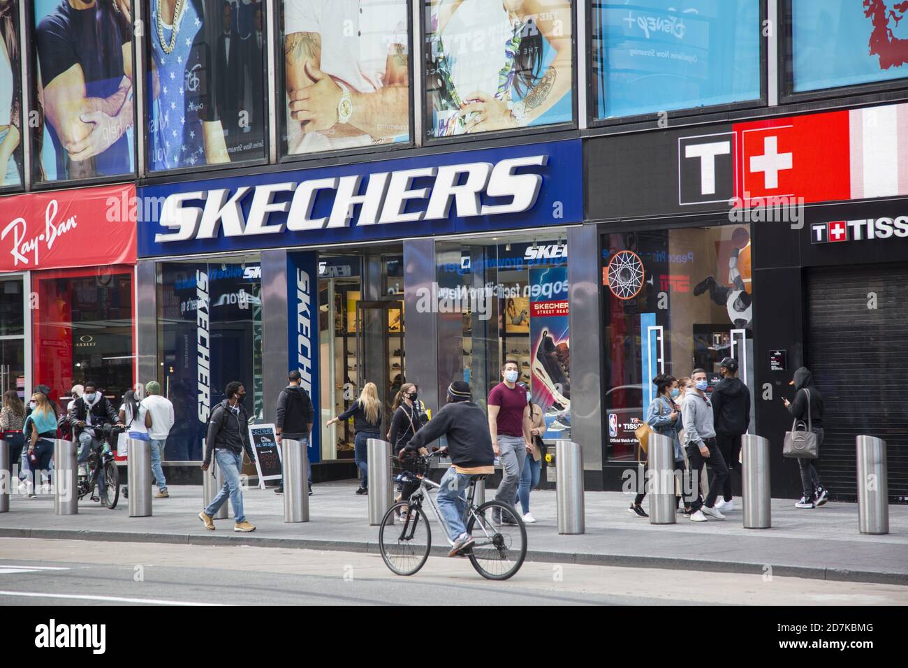 Die Leute laufen am Broadway entlang im Times Square Viertel vorbei an einem Sketchers Laden in Manhattan, New York City. Stockfoto