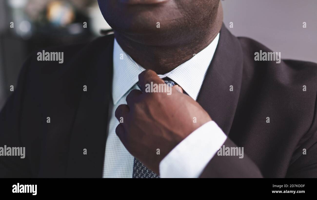 Schöner afrikanischer Mann in einem Anzug, der die Krawatte anpasst. Hochwertige Fotos Stockfoto