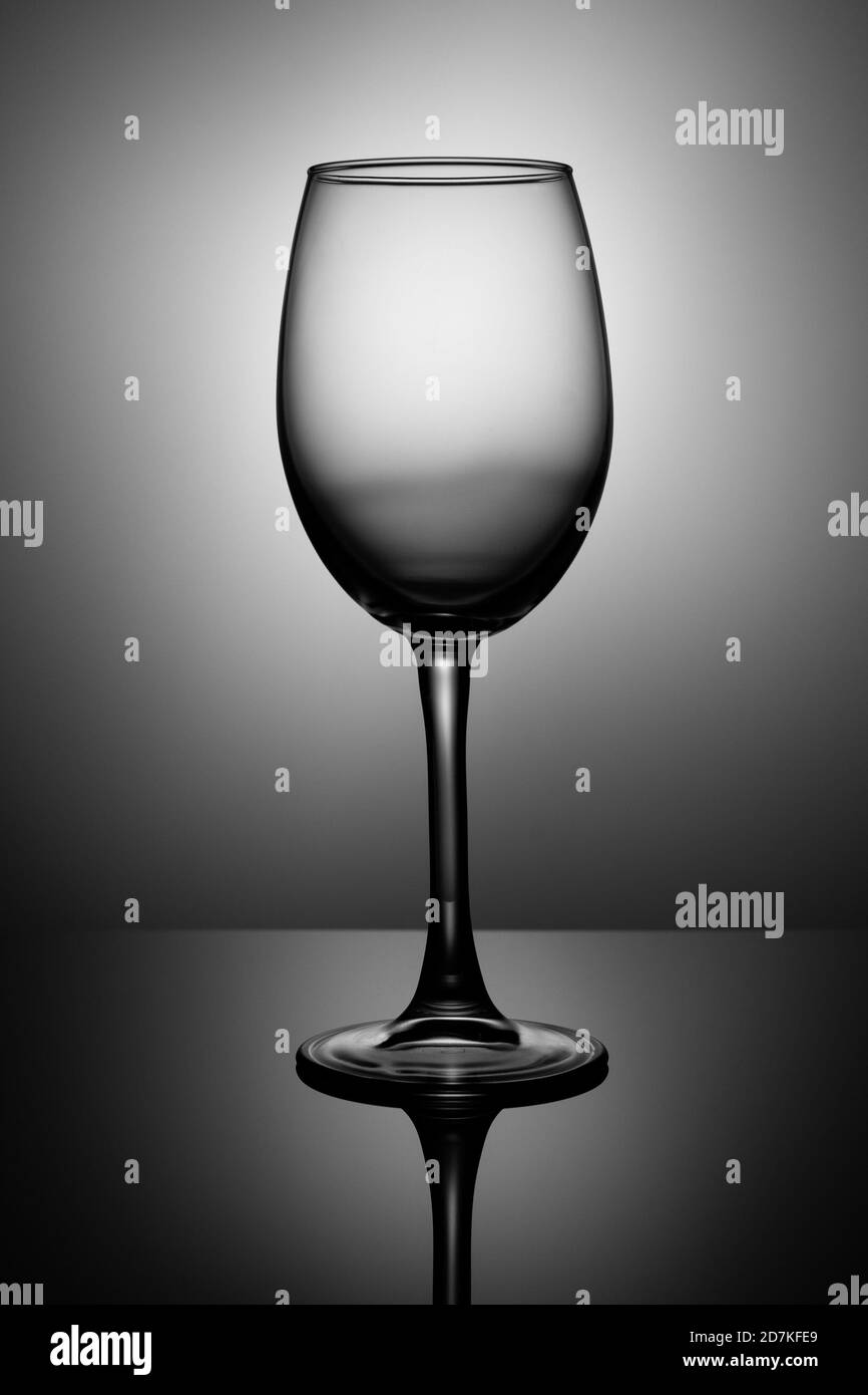 Transparentes Weinglas steht auf schwarzem Hochglanzglas Stockfoto