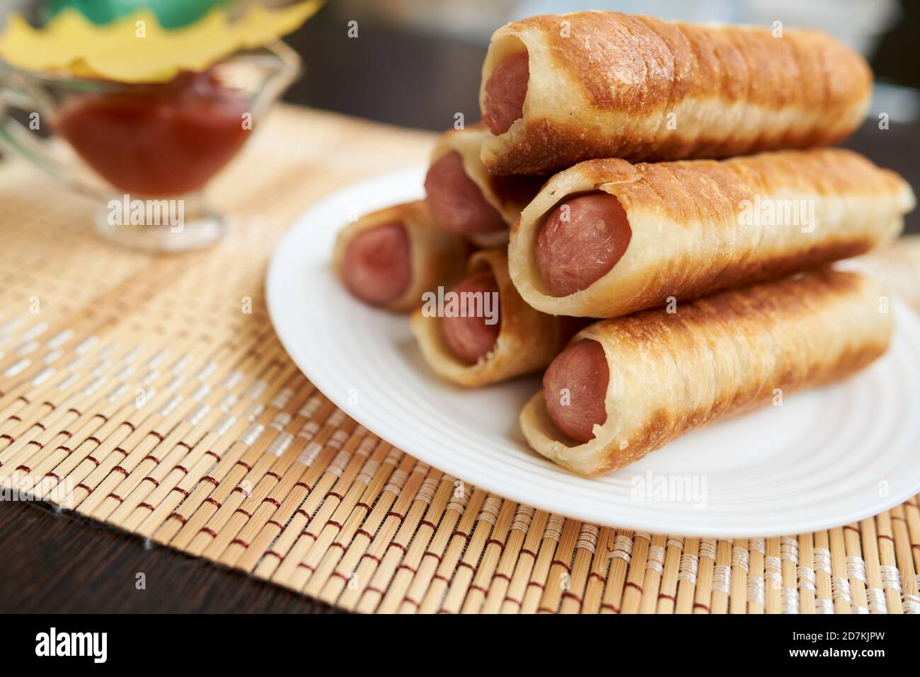 Würste in geröstetem Teig. Gebratene Pasteten mit Würstchen. Sie werden in dünne Streifen Butterteig gewickelt. Stockfoto