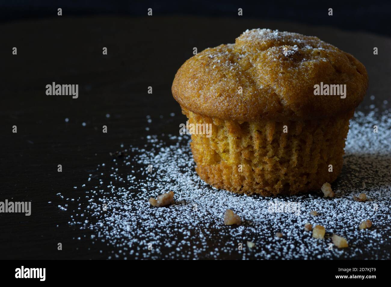 Kürbis-Muffin auf schwarzem Schiefer mit Puderzucker und Nüssen Stockfoto