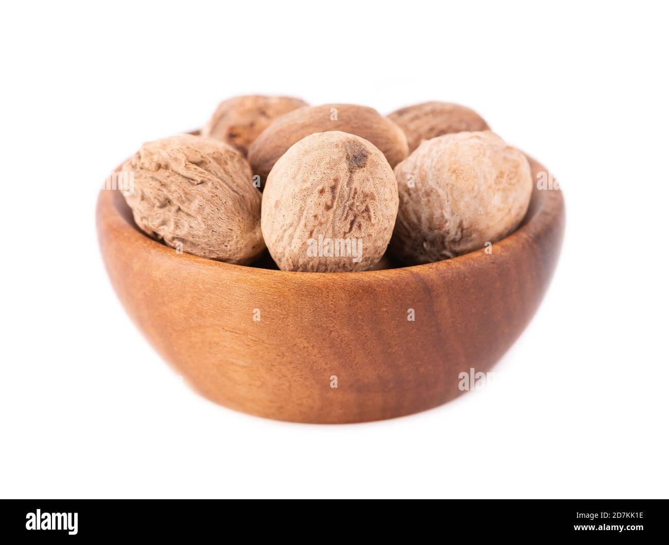 Muskatnuss isoliert auf weißem Hintergrund. Ganze Muskatnuss in Holzschüssel trocknen. Nahaufnahme. Stockfoto