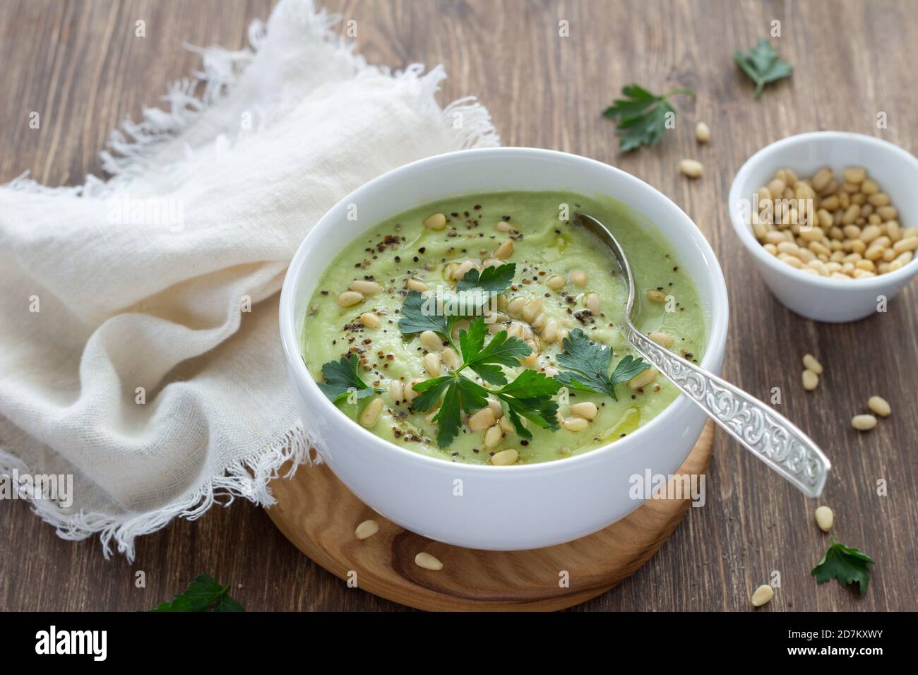 Blumenkohlpüree mit Petersilie und Pinienkernen in einer weißen Schüssel auf einem Holztisch. Köstliche Diät-Essen Stockfoto