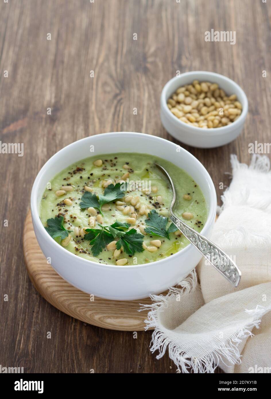 Blumenkohlpüree mit Petersilie und Pinienkernen in einer weißen Schüssel auf einem Holztisch. Köstliche Diät-Essen Stockfoto