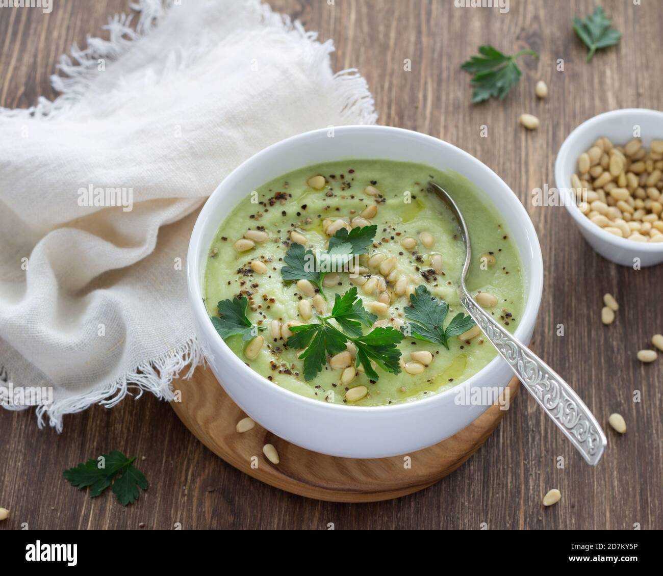 Blumenkohlpüree mit Petersilie und Pinienkernen in einer weißen Schüssel auf einem Holztisch. Köstliche Diät-Essen Stockfoto