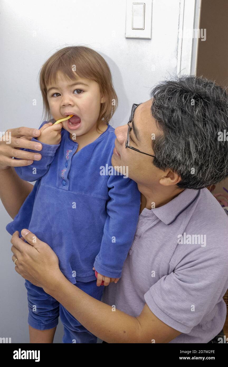 Ein Vater lehrt seine Kleinkindtochter, sich vor dem Schlafengehen die Zähne zu putzen. Foto von Liz Roll Stockfoto