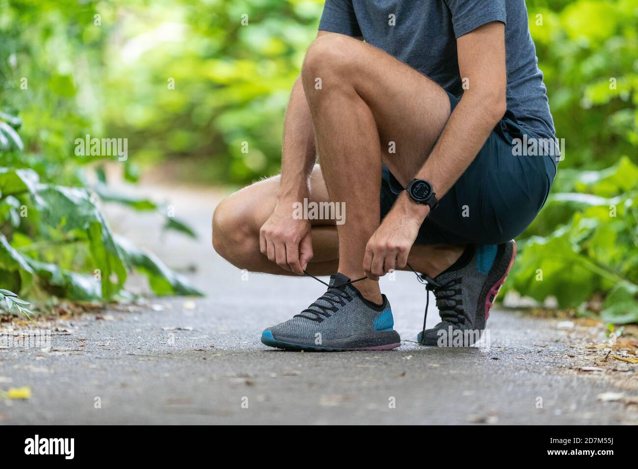 Running fit Mann binden Schuhe tragen tragbare Technologie Smart Watch. Fitness-Läufer Sportler, die sich für den Marathonstart im Frühjahr Herbst vorbereiten Stockfoto
