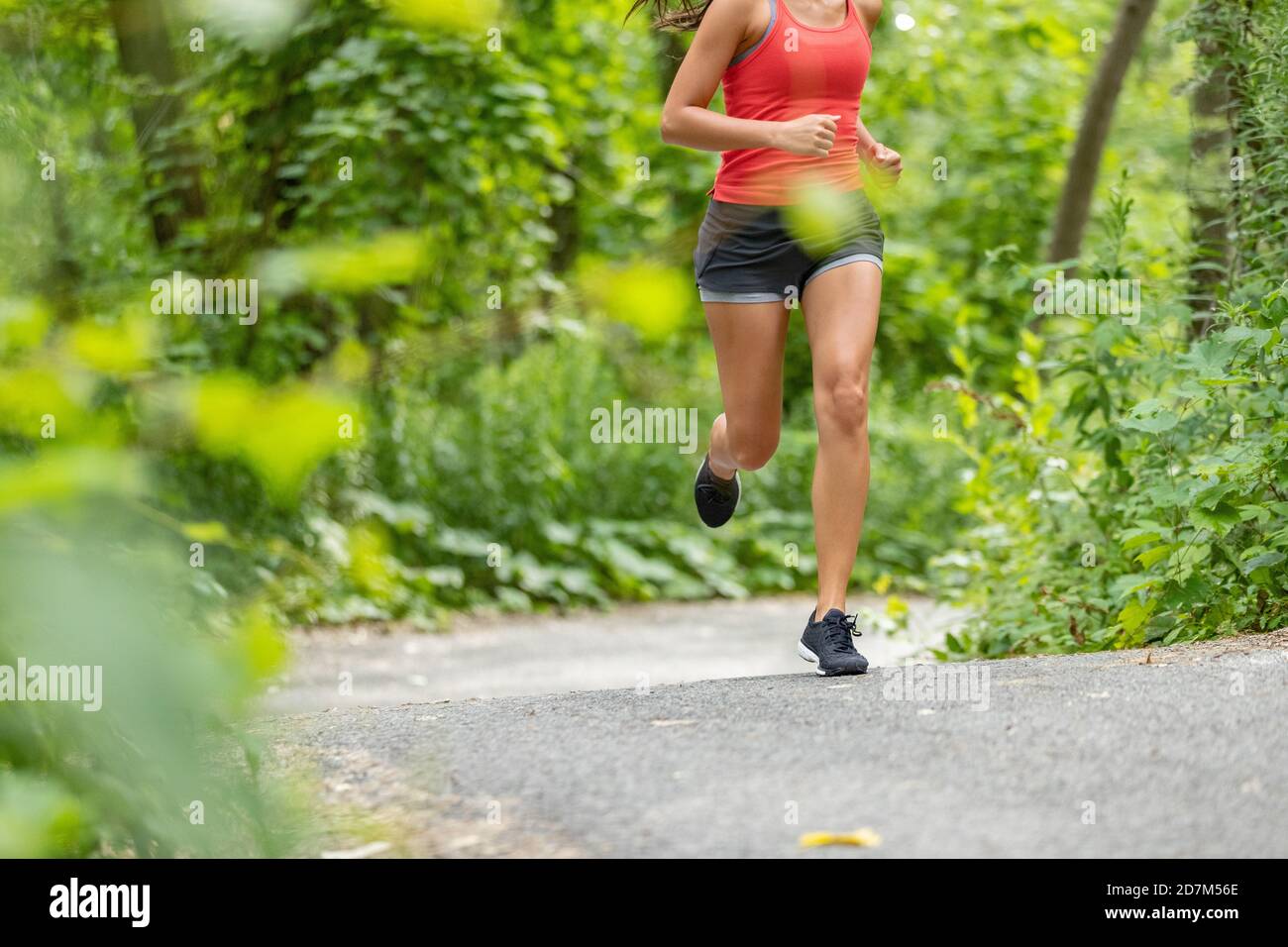 Laufsportlerin Frau auf Laufweg Joggen Nahaufnahme des Unterkörpers Oberschenkel, Beine, Laufschuhe im Wald. Stockfoto