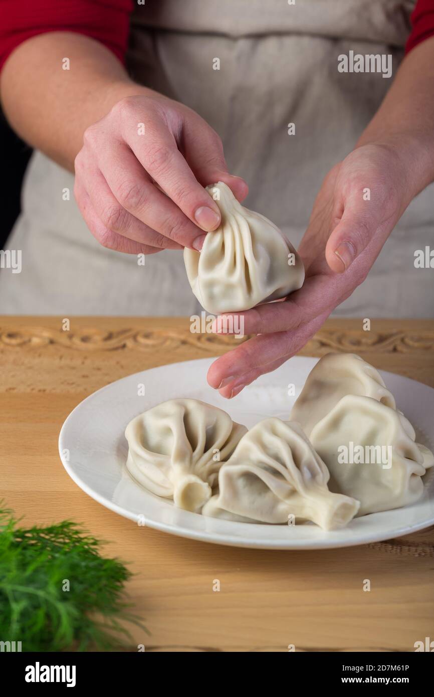 Khinkali, georgianische Knödel. Mann, der ein Khinkali in der Hand hält Stockfoto