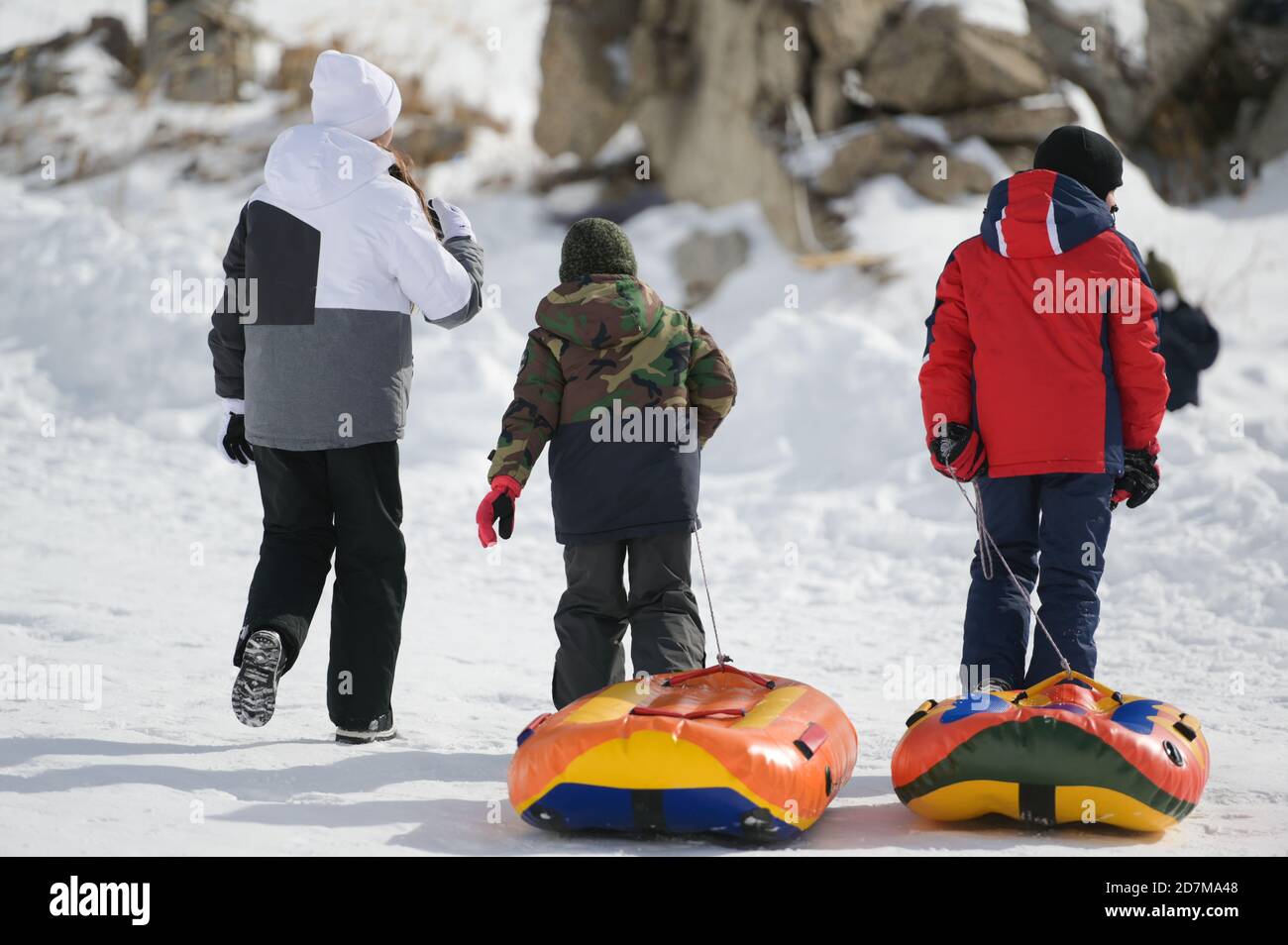Drei aktive Kinder in Skianzügen wandern auf weißem Schnee Mit Gummischläuchen auf Berg Winter alpinen Resort während der Outdoor Freizeitaktivitäten Stockfoto