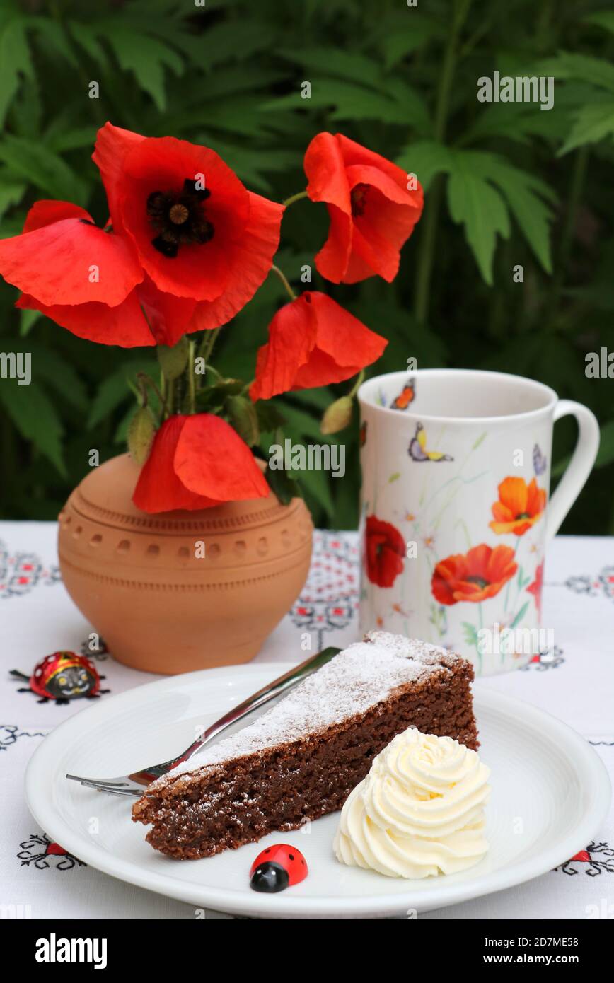 Tischdekoration mit einem Stück Schokoladenkuchen und Mohnblumen Stockfoto