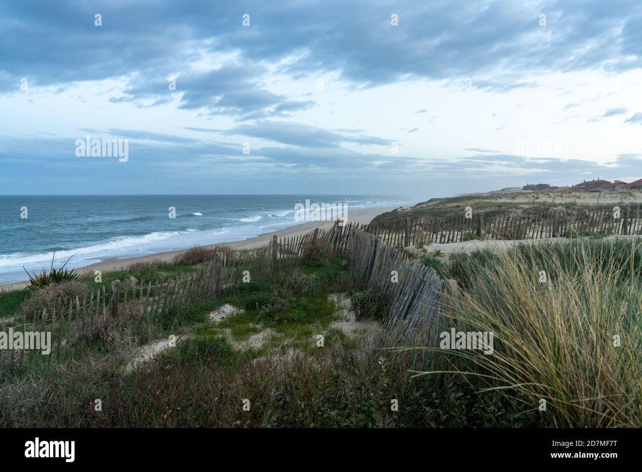 Sanddünen und Wellen brechen an einem endlosen Strand unter Ein stürmischer Himmel in Frankreich Stockfoto