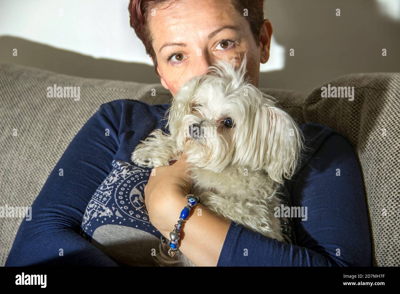 Frau, die einen maltesischen Hund in den Armen hält Stockfoto