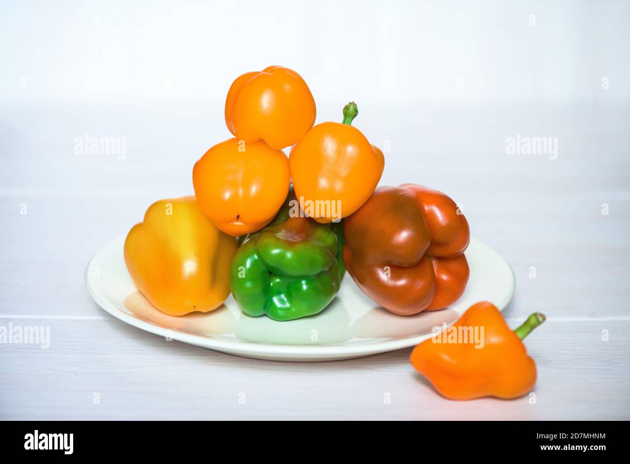 Pyramidenpfeffer rot, orange und grün auf einem Teller auf weißem Hintergrund Stockfoto