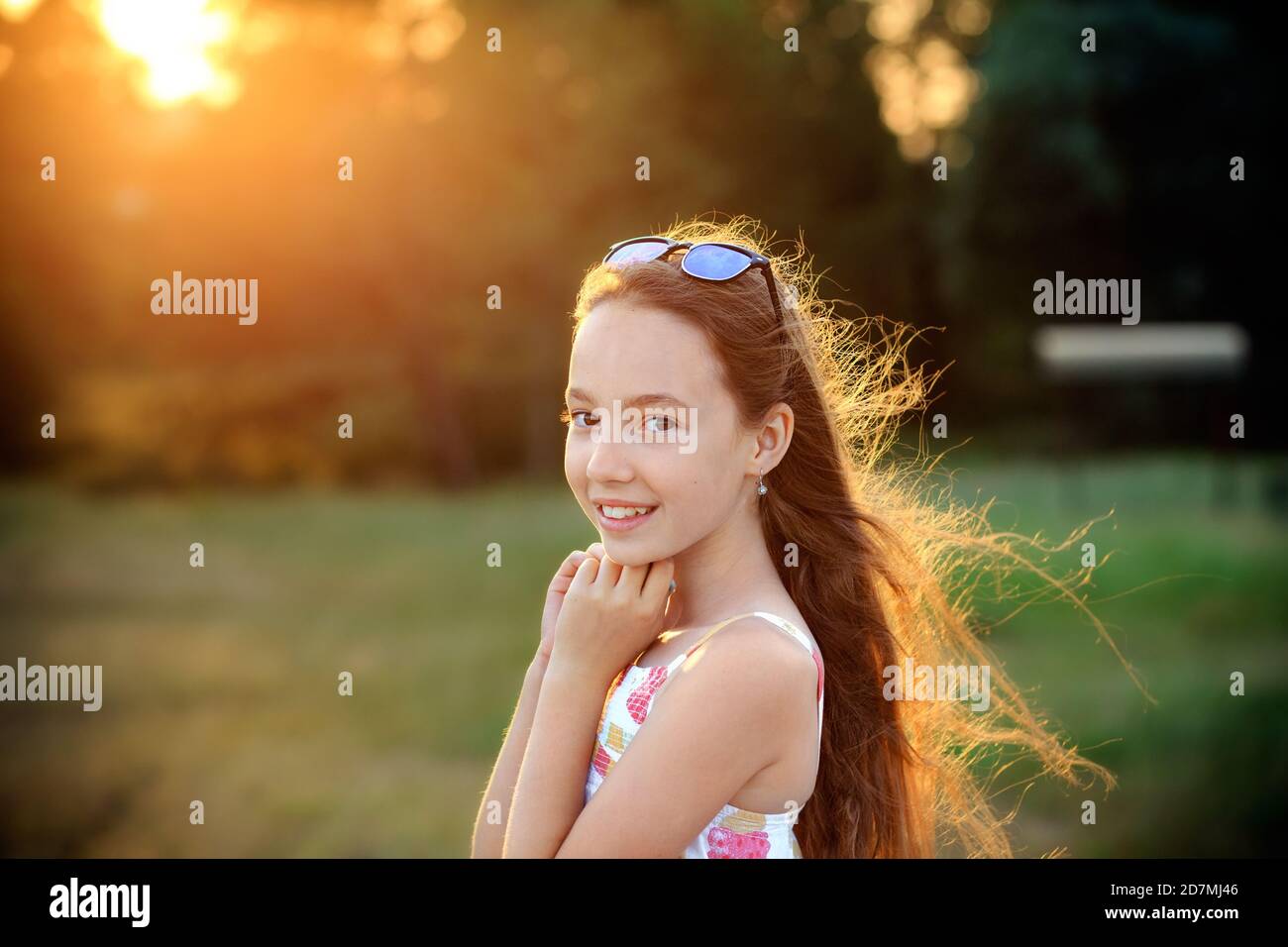 Das schöne Teen Girl lächelt und genießt die Natur im Park bei Sonnenuntergang Stockfoto