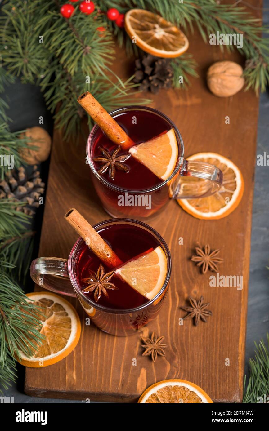 Weihnachtlicher Rotwein Glühwein mit duftenden Gewürzen und Zitrusfrüchten auf einem Holztisch, Nahaufnahme. Traditionelles Heißgetränk zu Weihnachten Stockfoto