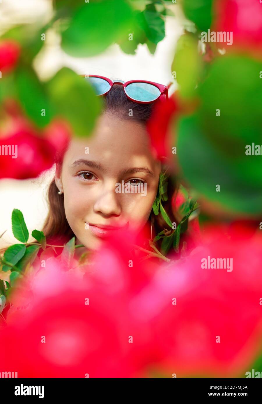 Porträt eines süßen Teenager-Mädchens, das auf den Rosen lächelt Stockfoto