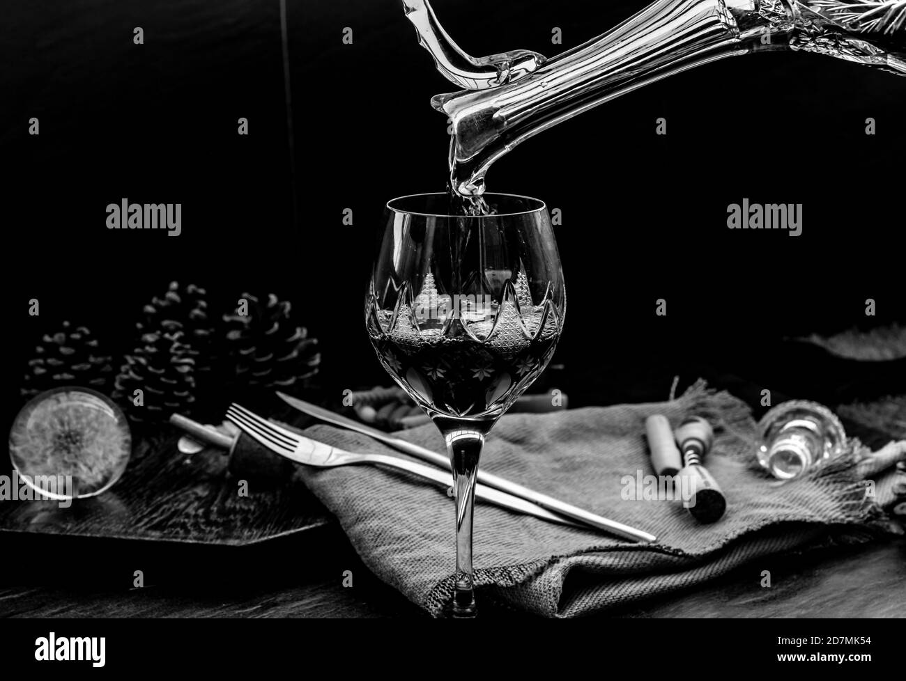 Schwarz-Weiß-Bild von Flat Lay Zusammensetzung mit Gießen Rotwein aus Krug in die Weinglas : traditionelle Weinbereitung und Weinprobe concep Stockfoto