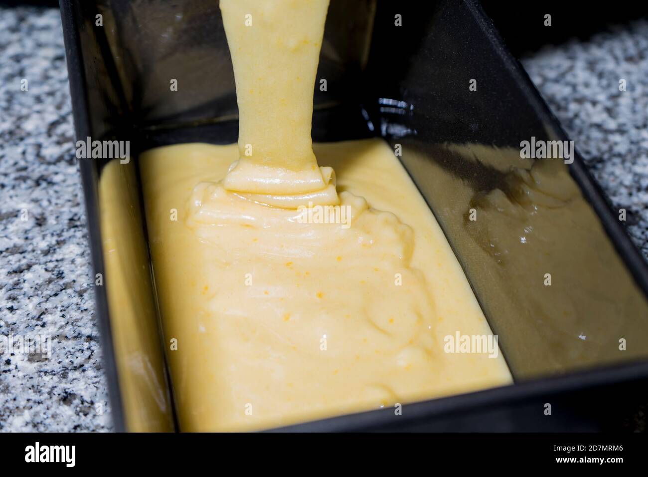 Der Biskuitteig wird in eine Kuchenform gegossen. Stockfoto