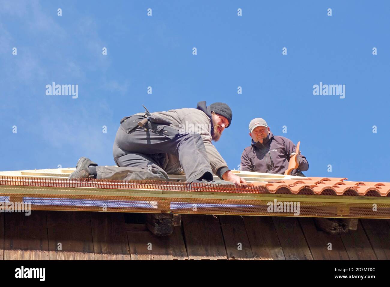 Dachauftragnehmer bei der Neulackung des Dachs auf dem Stall Stockfoto