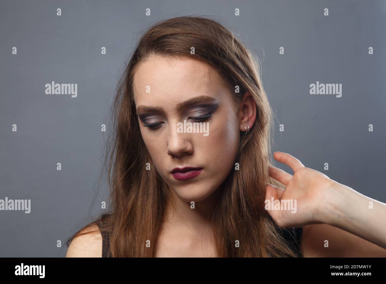 Bild von Mädchen berühren ihre Haare mit lila Lippen auf Grauer Hintergrund Stockfoto