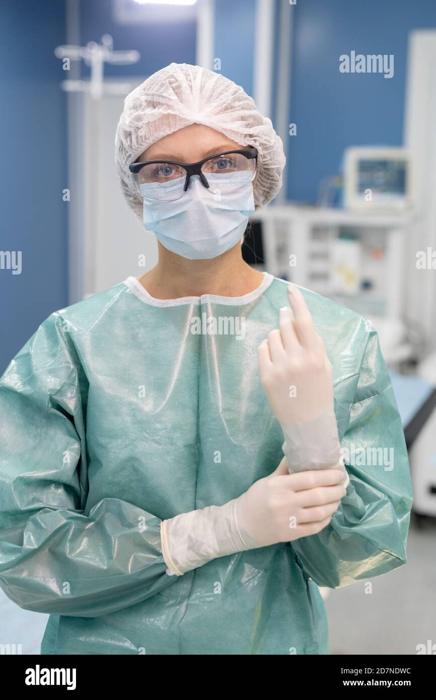 Junge professionelle Chirurg in schützende Arbeitskleidung im Operationssaal stehen Stockfoto