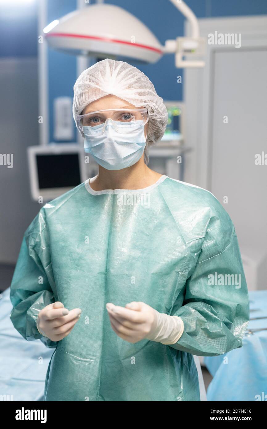 Junge zeitgenössische Chirurgen in Schutzhandschuhen, Maske und Brille Stockfoto