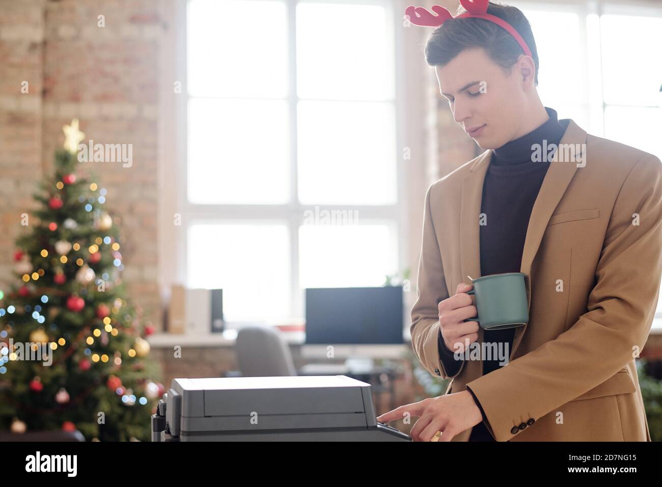 Junge elegante Geschäftsmann in Weihnachten Stirnband Druckknopf von xerox Maschine Stockfoto