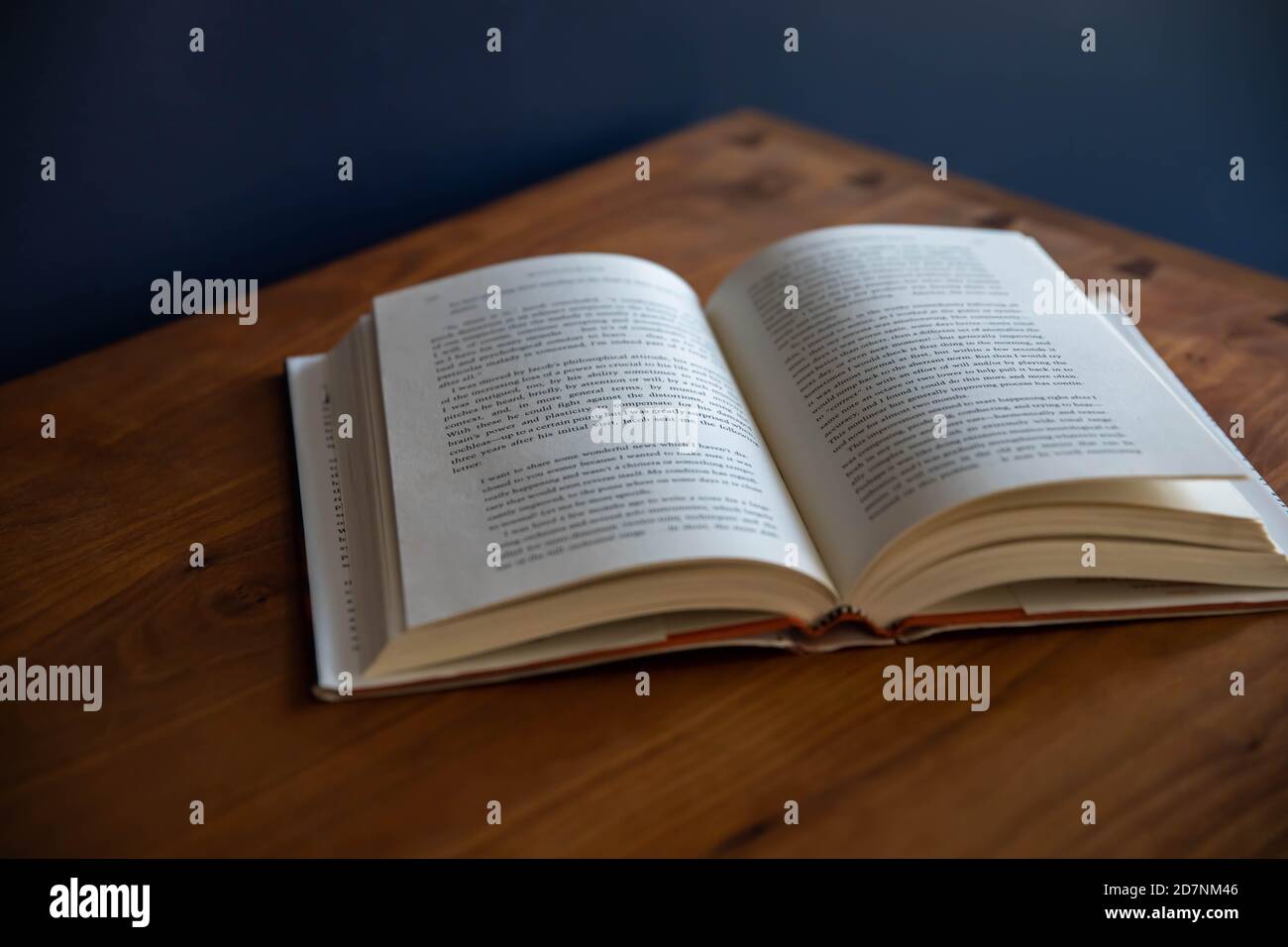 Offenes Buch auf einem Kirschholzschrank mit marineblauen Wänden Stockfoto