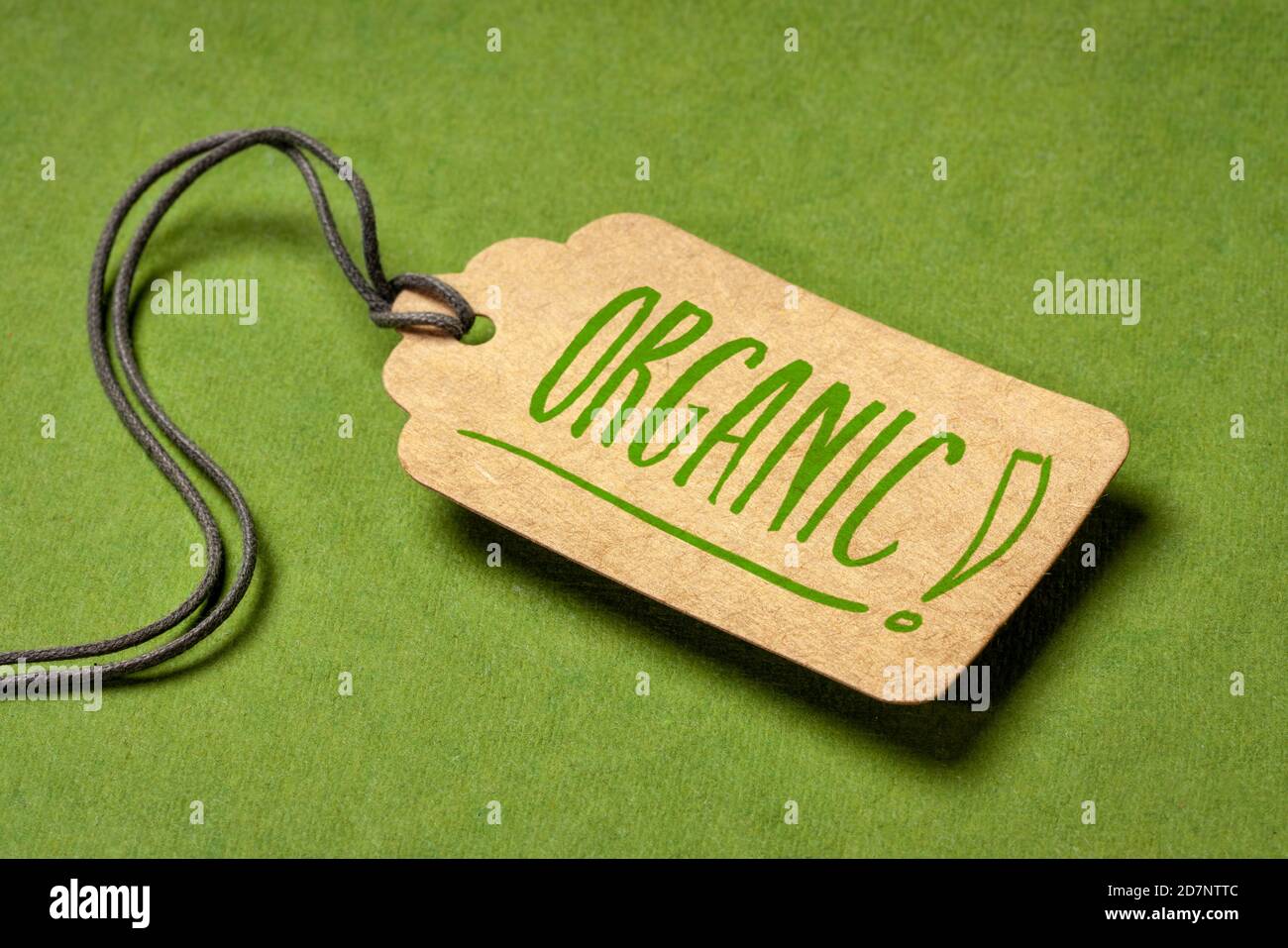 Organischer Text auf einem Papierpreisschild mit einem Garn gegen strukturiertes grünes Papier, bewusstes Einkaufskonzept Stockfoto