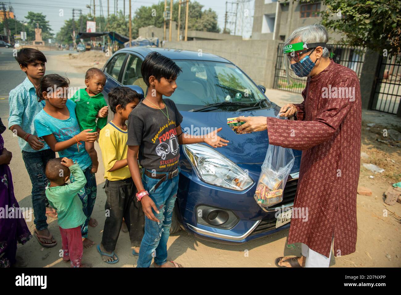 Ghaziabad, Indien. Okt. 2020. Ein alter Mann mit Gesichtsmast wird gesehen, wie er Kekspakete an obdachlose Kinder und Familien verteilt, während Navaratri eines der prominenten Hindu-Festivals. Nächstenliebe hat große Bedeutung in hinduistischen Schriften vor allem während der Festivals, wie es gilt als ein gutes Karma (Tat). Kredit: SOPA Images Limited/Alamy Live Nachrichten Stockfoto