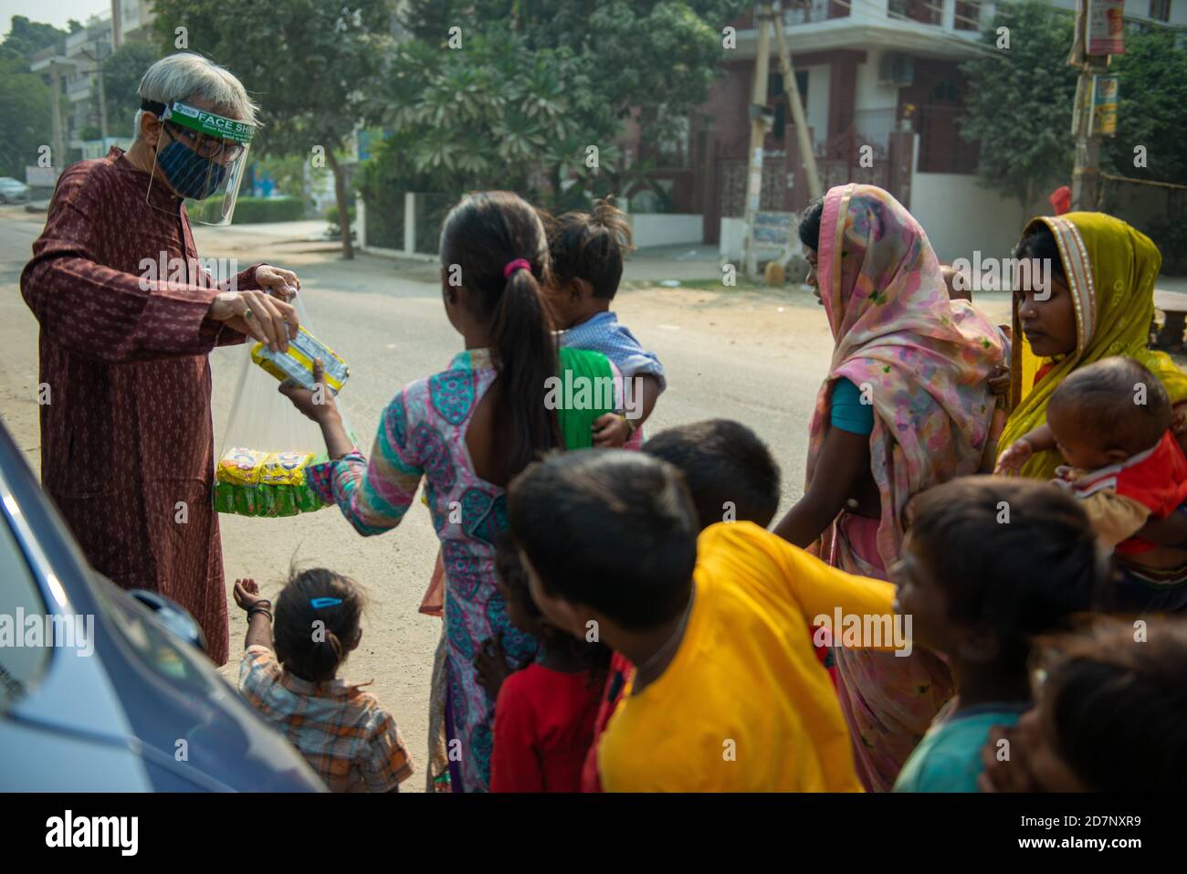 Ghaziabad, Indien. Okt. 2020. Ein alter Mann mit Gesichtsmast wird gesehen, wie er Kekspakete an obdachlose Kinder und Familien verteilt, während Navaratri eines der prominenten Hindu-Festivals. Nächstenliebe hat große Bedeutung in hinduistischen Schriften vor allem während der Festivals, wie es gilt als ein gutes Karma (Tat). Kredit: SOPA Images Limited/Alamy Live Nachrichten Stockfoto